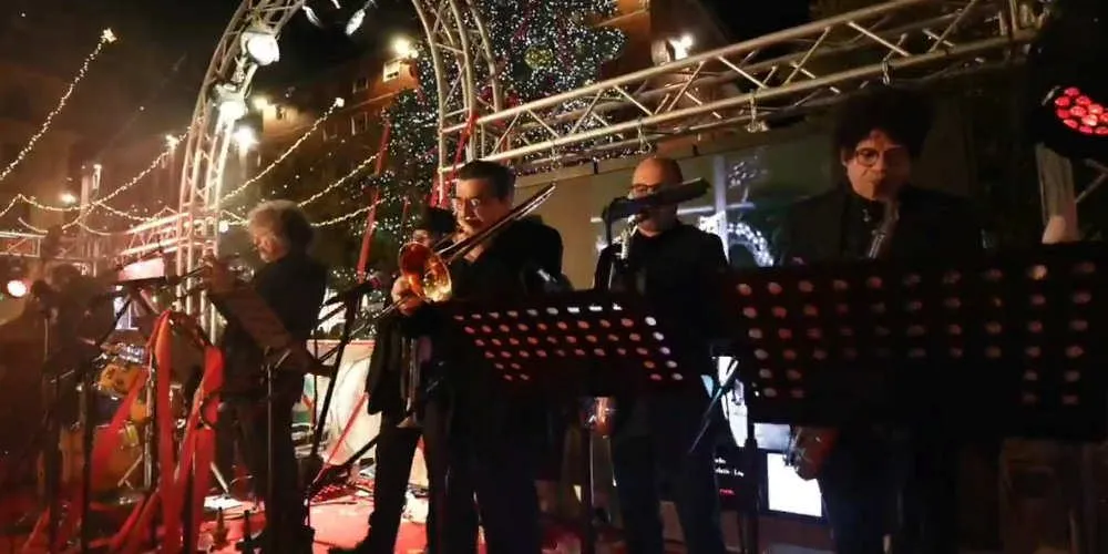 Una band sul palco sotto una struttura con le luci di Natale