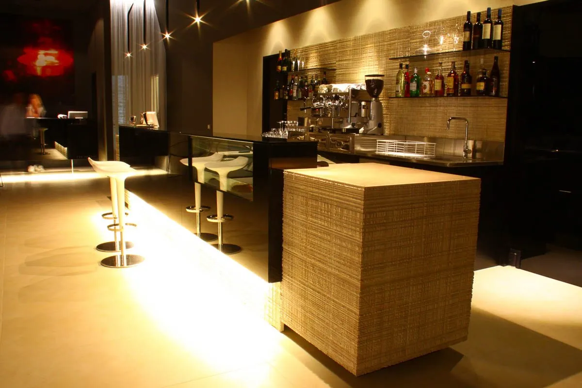 Il bancone di un bar in legno chiaro con le luci calde