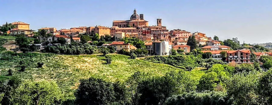 Un borgo marchigiano tra le colline, con le case in pietra sul crinale