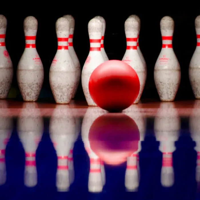 I birilli del bowling con la palla rossa riflessi sul pavimento