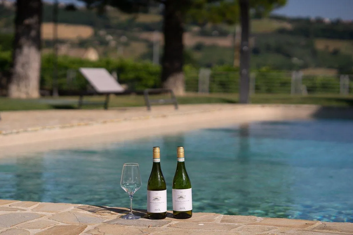 Due bottiglie di Verdicchio e un calice a bordo piscina