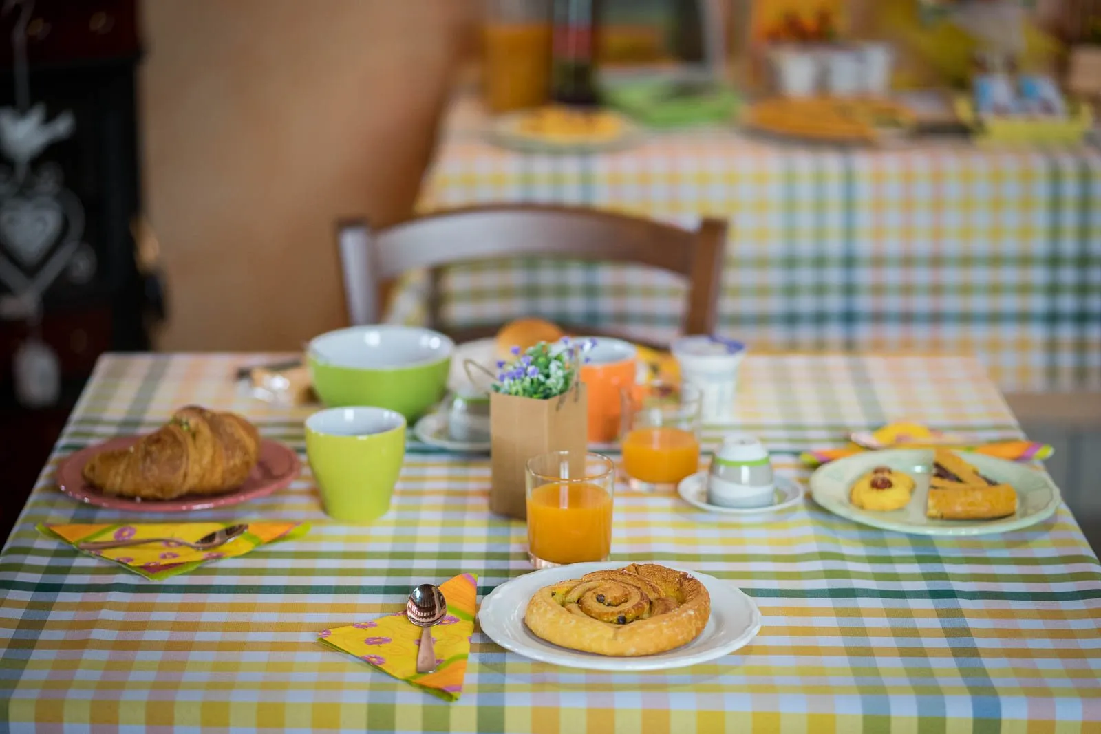 Una tavola per la colazione con la tovaglia a quadri, il croissant e il succo d'arancia