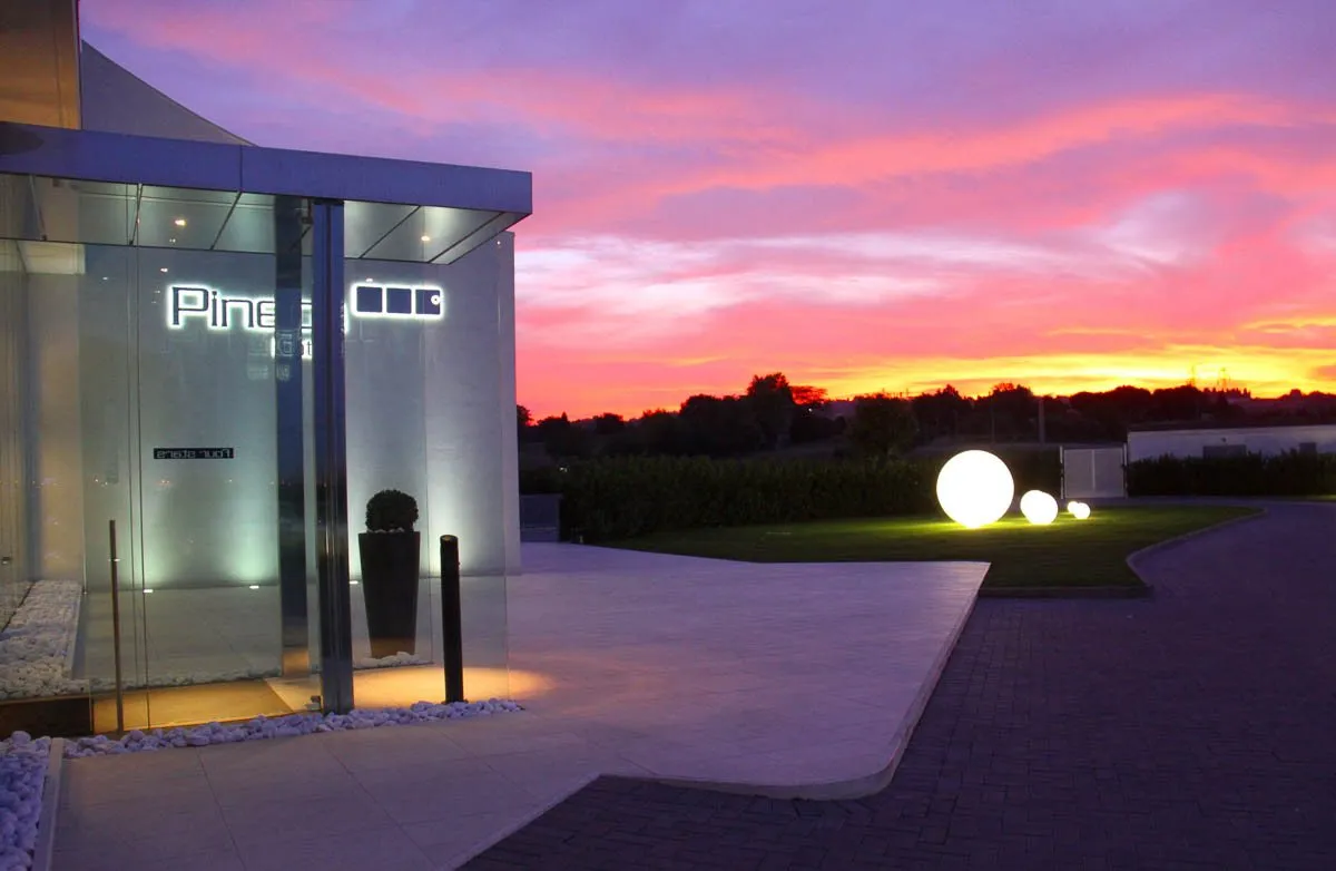 Un edificio con le vetrate illuminate al tramonto, e una grande sfera luminosa