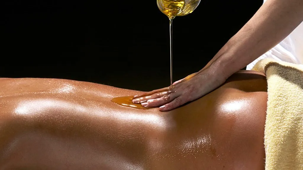 Una mano che stende l'olio sulla schiena durante un massaggio