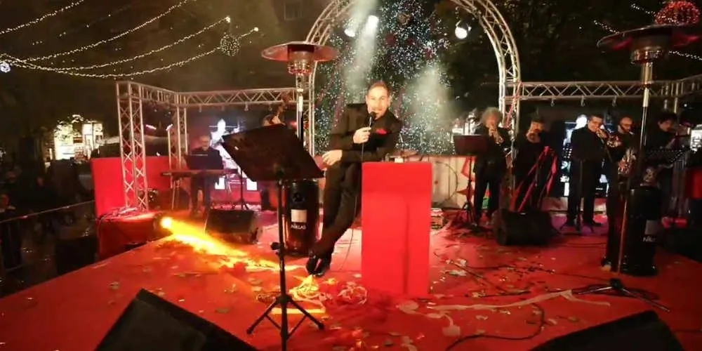Un palco con il tappeto rosso e le luci di Natale, durante un concerto in piazza