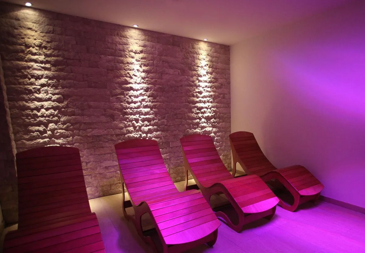 Una sala relax con le sdraio in legno e le luci viola