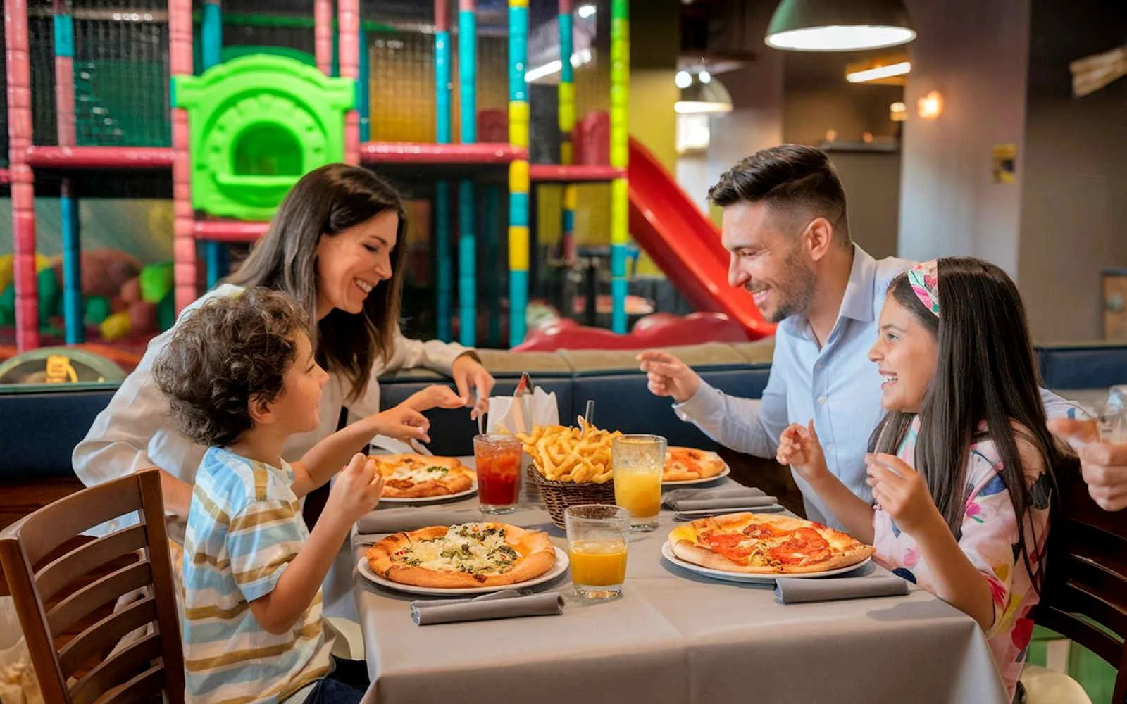 Una famiglia a tavola in un ristorante con parco giochi