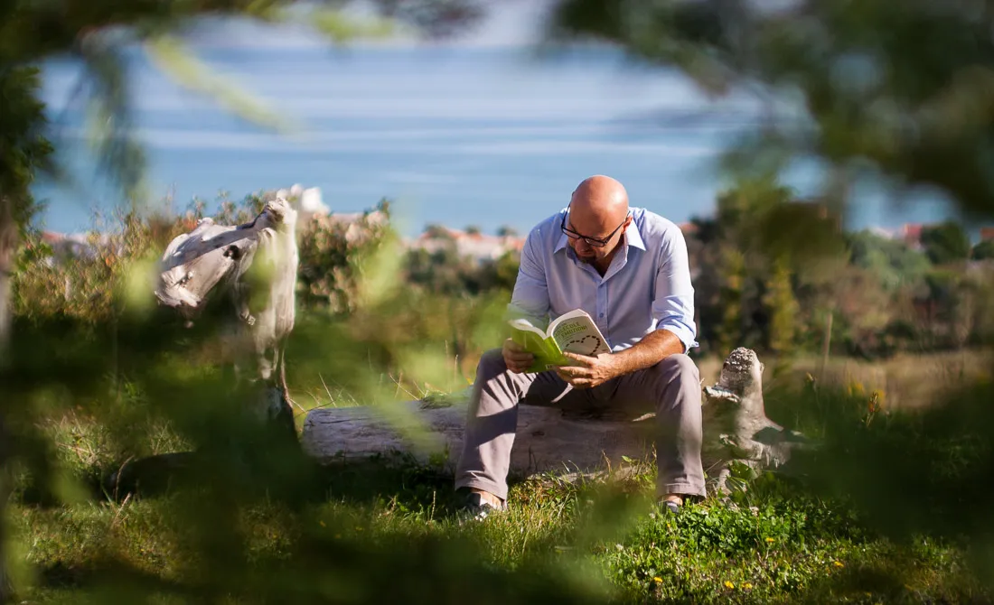 Roberto Romagnoli seduto sull'erba con un libro in mano