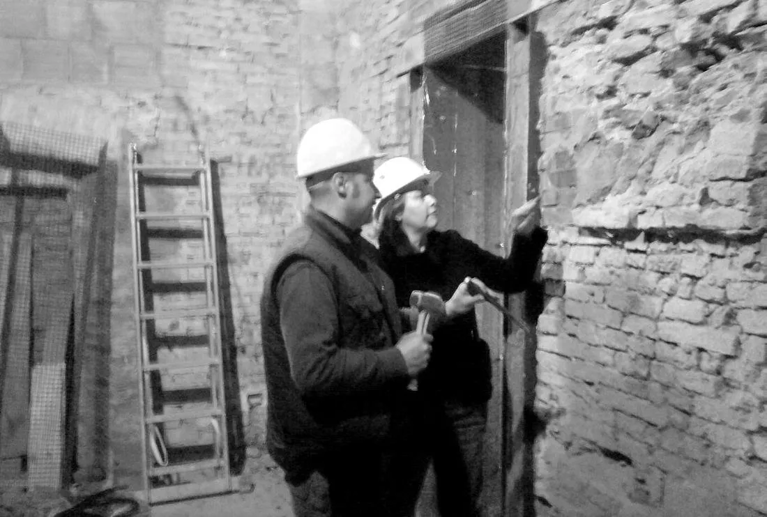 Due persone con il casco durante un sopralluogo in cantiere, in bianco e nero