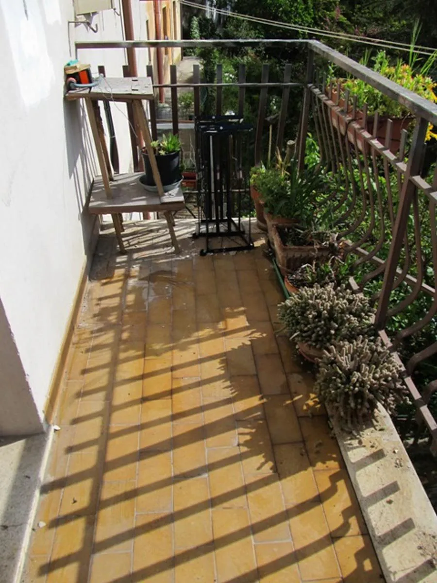 Un terrazzo con la pavimentazione in legno e la ringhiera, dopo il risanamento
